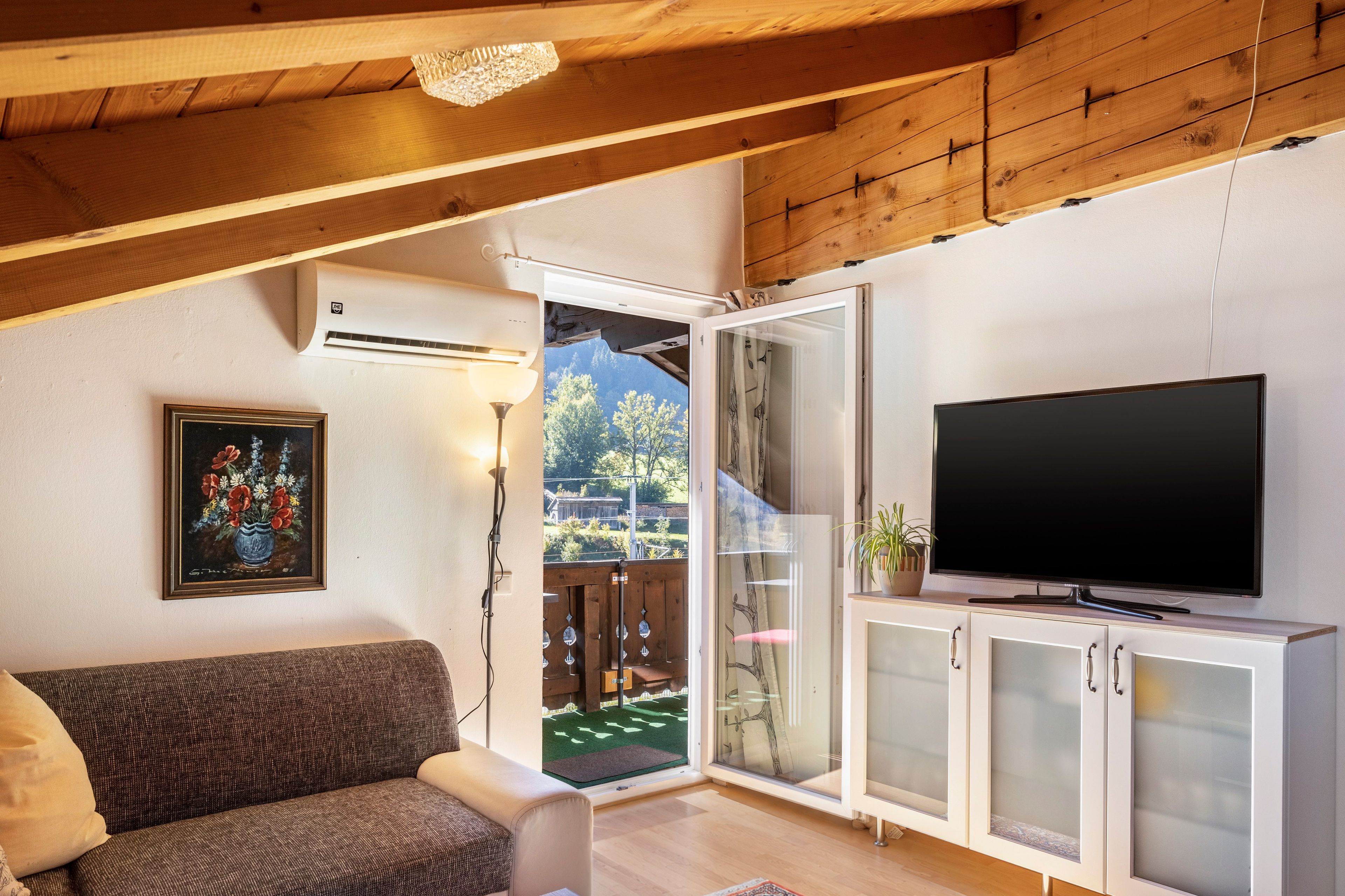 Una sala de estar con sofá, televisión y un cuadro.