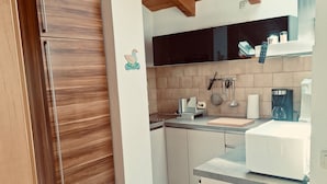 Una cocina con armarios de madera, salpicadero de azulejos, un microondas y una ventana sobre el fregadero.