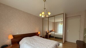 Une chambre à coucher avec un grand lit, des lampes de chevet, une table de chevet en bois, une commode et un miroir.