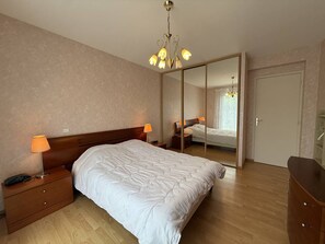 A bedroom with a large bed, bedside lamps, a wooden nightstand, a dresser, and a mirror. - Large house with parking - 9 guests (Trégastel)