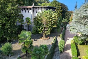 A building with a garden, a central tree, and a pathway.