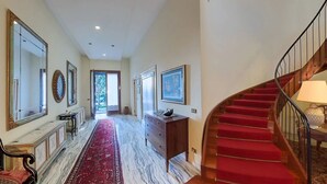 A hallway with a red carpet, marble floor, a wooden bench, a dresser, and a staircase with red carpet. - Luxury Lakeside Retreat with a Pool near Stresa! Lake Maggiore Villa Romanza (Stresa)