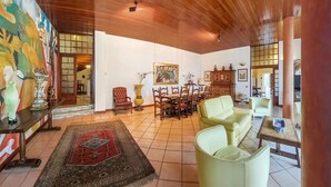 A spacious living room with a wooden ceiling, a dining area with a table and chairs, and a large painting on the wall. - Luxury Lakeside Retreat with a Pool near Stresa! Lake Maggiore Villa Romanza (Stresa)