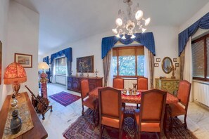 A dining room with a chandelier, a table set for four, and a view of the outdoors through a window. - Luxury Lakeside Retreat with a Pool near Stresa! Lake Maggiore Villa Romanza (Stresa)