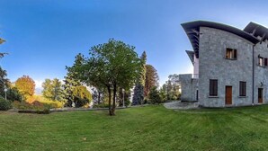 A modern building with a curved roof, a stone facade, and a well-maintained lawn. - Luxury Lakeside Retreat with a Pool near Stresa! Lake Maggiore Villa Romanza (Stresa)