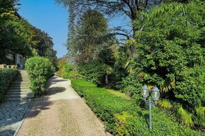 Un vialetto lastricato circondato da vegetazione lussureggiante e un edificio sulla sinistra.