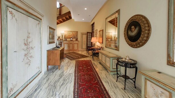 A hallway with a marble floor, a red rug, a wooden cabinet, a table with a lamp, and a large mirror. - Luxury Lakeside Retreat with a Pool near Stresa! Lake Maggiore Villa Romanza (Stresa)