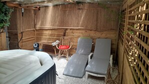 Ein Spa-Bereich mit Whirlpool, zwei Liegesesseln, einem kleinen Tisch und einem Sessel.