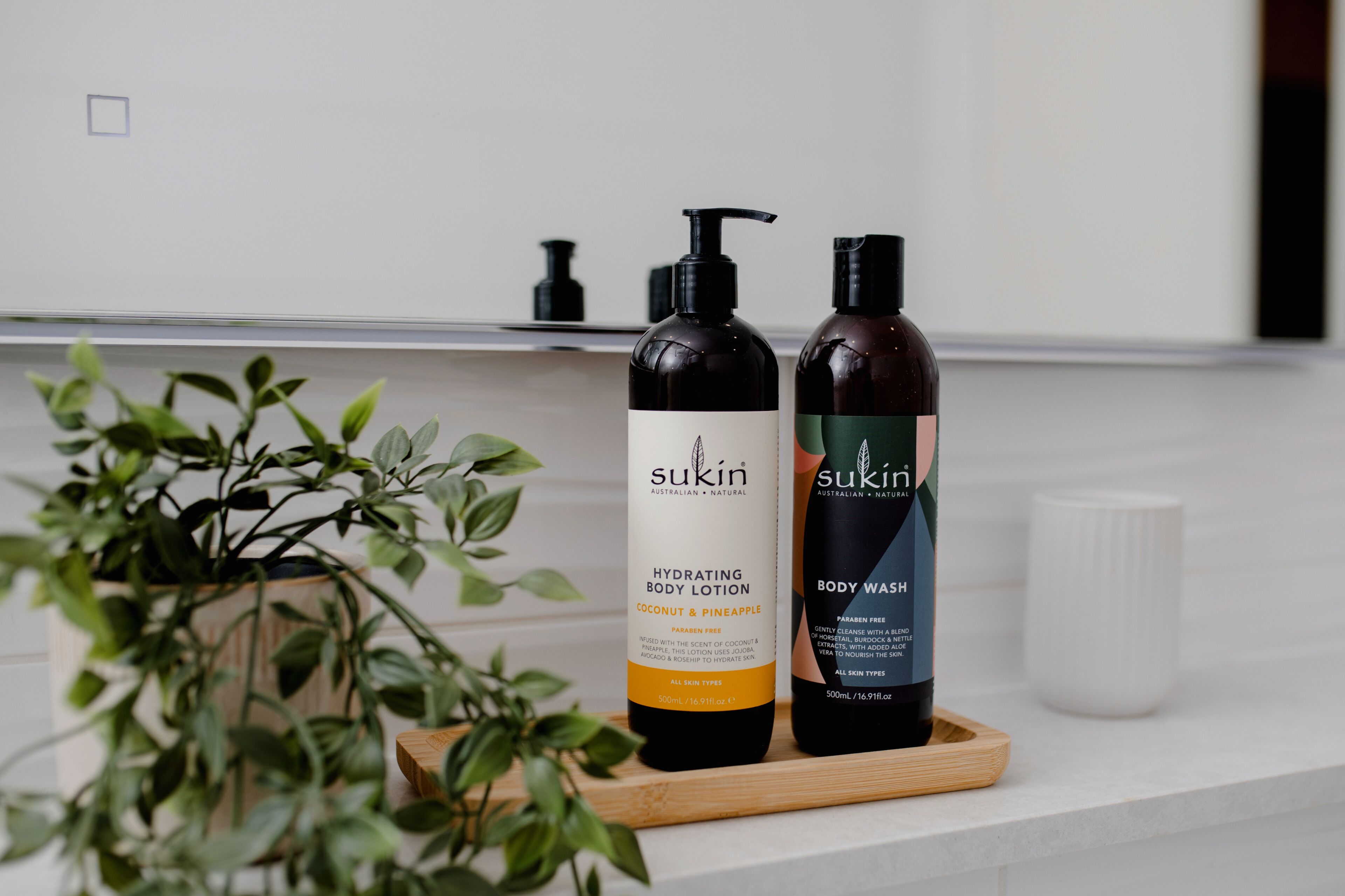 Two bottles of Sukin body wash on a wooden tray.