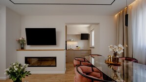 En moderne stue med et glasbord, behagelige møbler, et fladskærms-tv og en pejs.