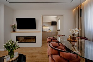 Ein modernes Wohnzimmer mit einem Glastisch, bequemen Sitzgelegenheiten, einem Flachbildfernseher und einem Kamin.