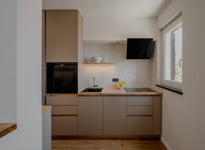 Eine kompakte Küche mit eingebautem Ofen, Spüle und Fenster.