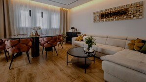 En moderne stue med sofa, sofabord, spisebord med stole og et dekorativt vægkunstværk.