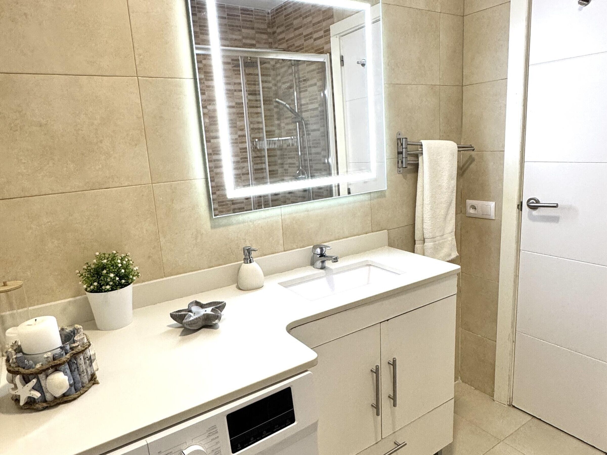 A bathroom with a white sink, a mirror, a shower, and a door.