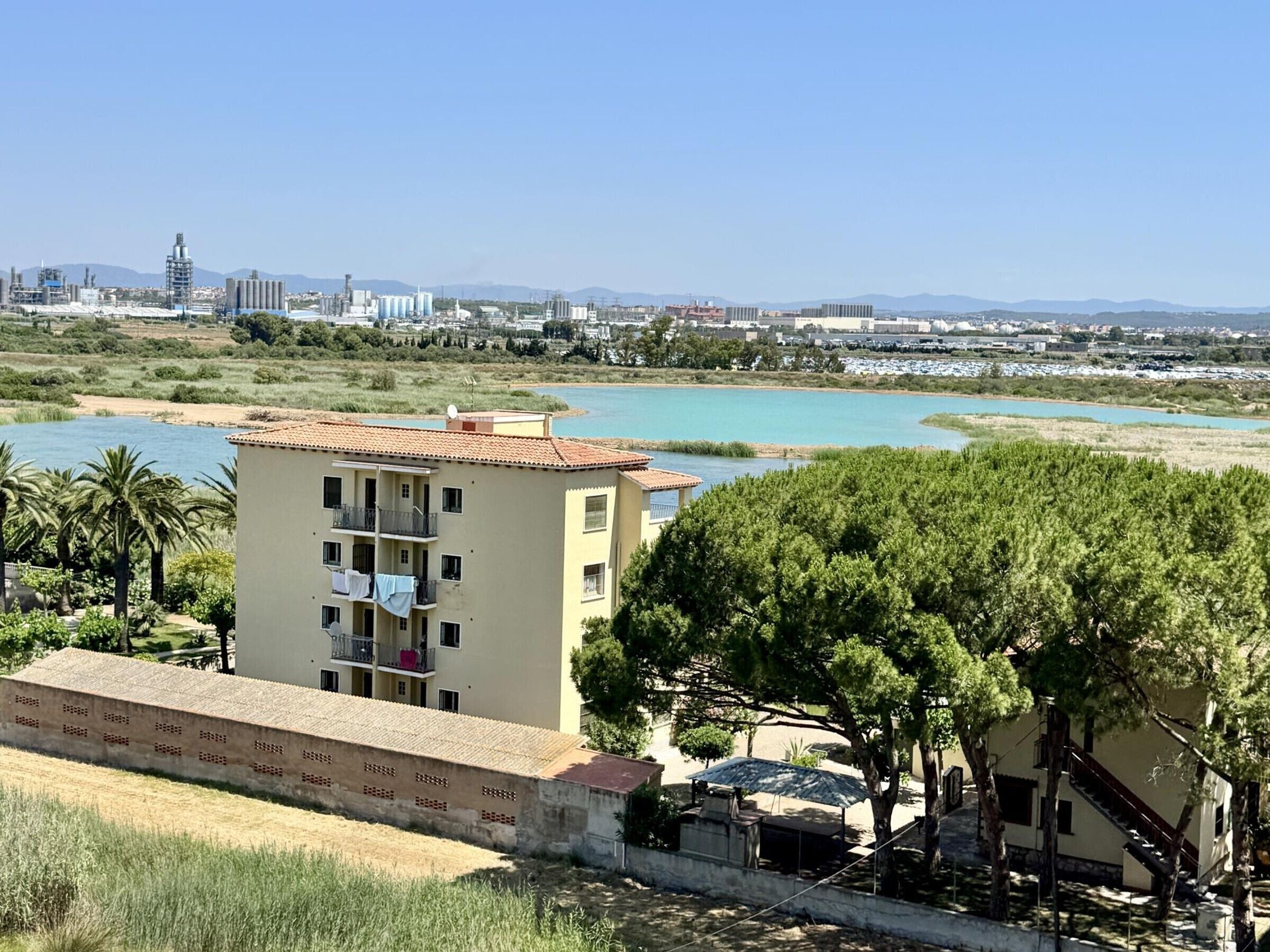 Un edificio con balcones, vistas a una masa de agua y un horizonte urbano distante.