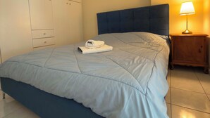 Un dormitorio con una cama, una mesita de noche, una lámpara, un armario y dos cuadros decorativos.