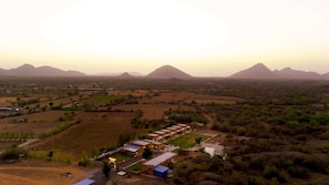 An aerial view of a rural area with a row of buildings, possibly a resort or lodge, surrounded by fields and mountains.