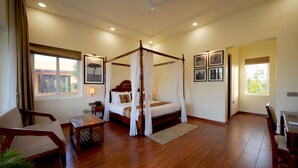 Une chambre spacieuse avec un lit à baldaquin, un plancher en bois et de grandes fenêtres.