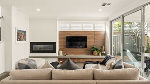Un salon moderne avec un canapé, un téléviseur à écran plat et un mur décoratif en bois.