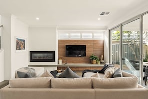 Ein modernes Wohnzimmer mit einer Couch, einem Flachbildfernseher und einer Wand im Holzdesign.