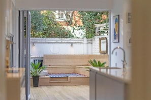 A modern kitchen with a wooden bench, potted plants, and a view of the garden. - Stylish Windsor Home | Hot Tub | Town Centre (Windsor)