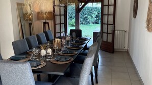 A dining area with a long table set for six, surrounded by chairs, with two hanging light fixtures above. - Villa Bonamour - Capbreton - Pool - Port - Beach (Capbreton)