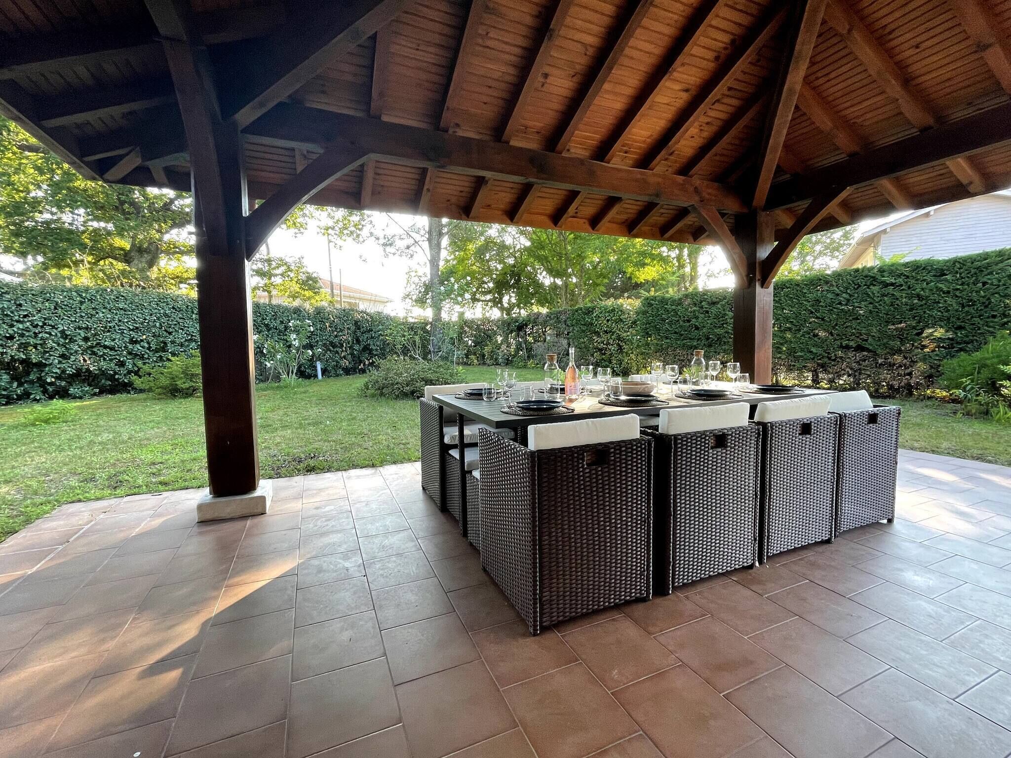 An outdoor dining area with a covered patio, a table set for four, and a garden view.