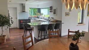 Una cocina moderna con una isla central, taburetes negros y una mesa de comedor con sillas.