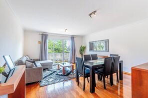 A modern living room with a sofa, coffee table, dining table with chairs, and a large window with curtains. - Sardonyx Scape Cancela Madeira by GRM near Funchal (Caniço)