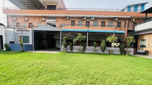 Un edificio con acceso cubierto, unidades de aire acondicionado y un área cercada con vegetación.