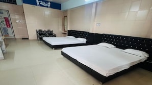 Habitación de hotel con dos camas, ventilador de techo y piso de baldosas.