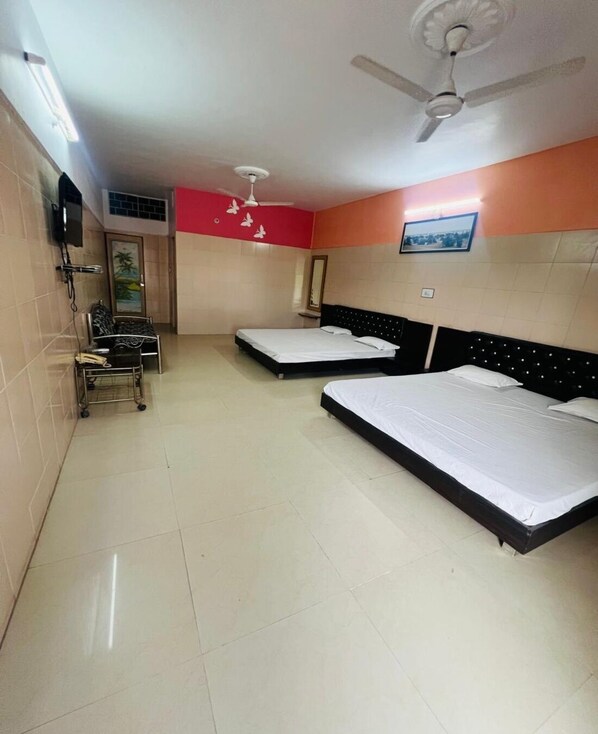 A hotel room with two beds, a ceiling fan, a TV, and a small desk with a chair.