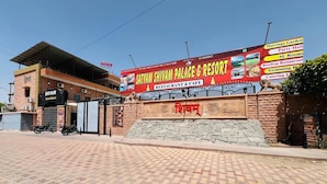 Un edificio con un cartel que dice 'Satyam Shivam Palace & Resort', que ofrece servicios como restaurante, cafetería y salón de bodas.
