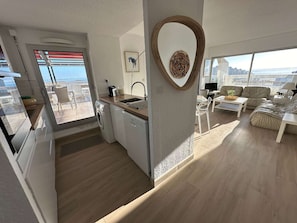 Ein moderner Wohnraum mit Küche, Essbereich und einem Balkon mit Blick auf die Stadt.