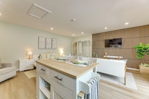 A modern hotel room with a kitchenette, a seating area, a flat-screen TV, and a large plant. - Patio & Grill! Modern Studio Near Sofi Stadium (Los Angeles)