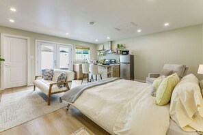 A bedroom with a bed, a desk, a chair, a sofa, and a kitchenette. - Patio & Grill! Modern Studio Near Sofi Stadium (Los Angeles)
