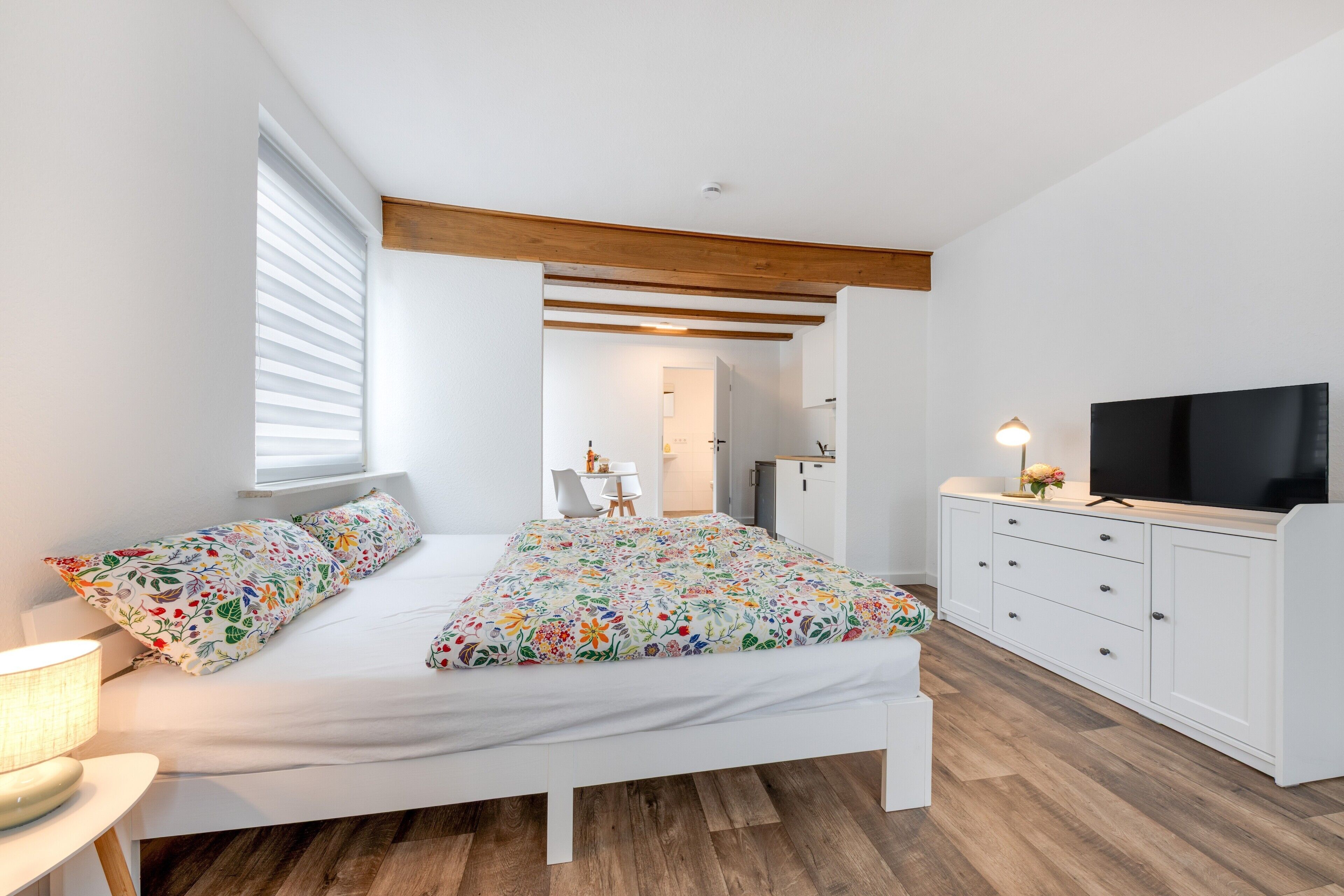 A bedroom with a bed, a TV, a desk, and a chair.