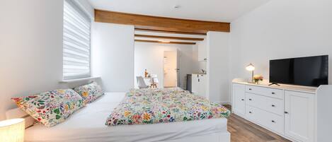A bedroom with a bed, a TV, a desk, and a chair.