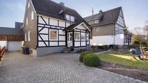 Une maison traditionnelle à colombages, avec une allée pavée et une petite pelouse.