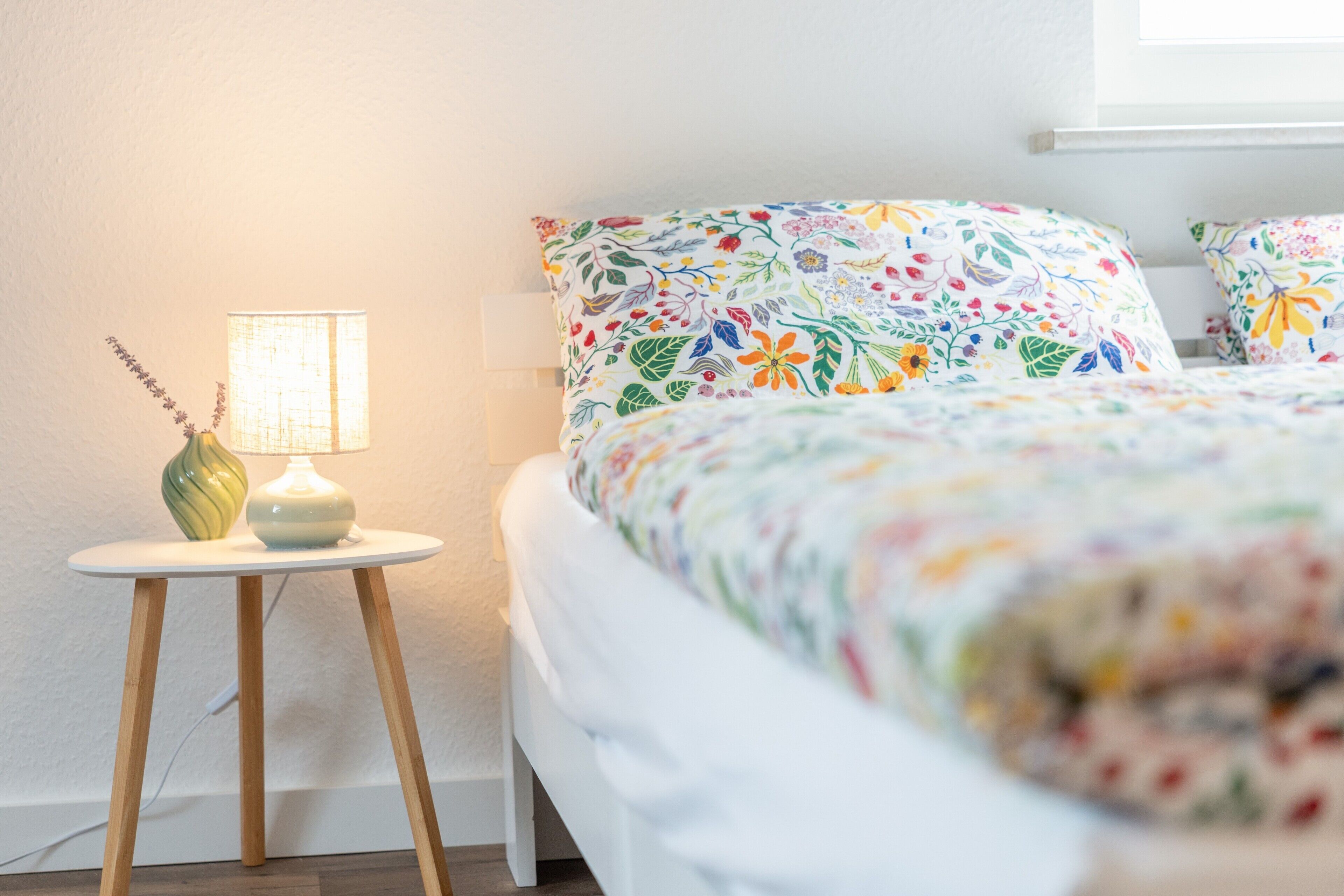Une chambre à coucher avec un lit, une table de chevet avec une lampe et une étagère fixée au mur.