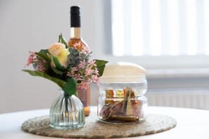A glass vase with flowers, a bottle, and a jar with candies on a woven placemat. - Apartment 'Huckelberg' with Wi-Fi (Schmallenberg)