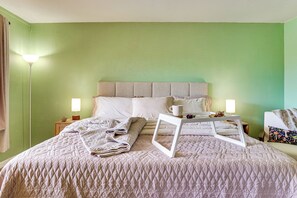 A neatly made bed with a quilted blanket, a bedside table with a lamp, and a framed picture on the bed. - Steps to Fashion Square! Condo w/ Patio & Pool (Scottsdale)