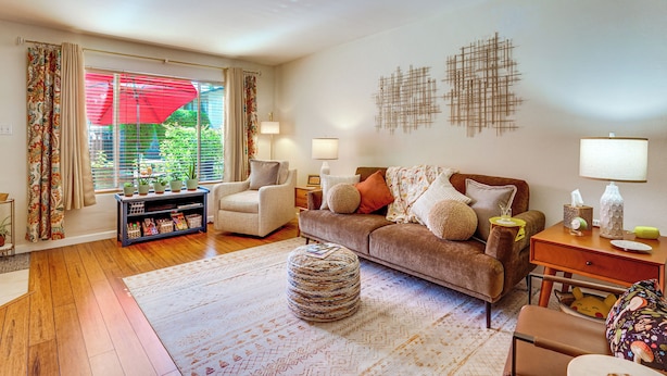 A living room with a sofa, armchairs, a coffee table, and a bookshelf. - Steps to Fashion Square! Condo w/ Patio & Pool (Scottsdale)