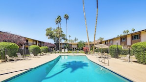 A swimming pool with lounge chairs, palm trees, and a building with a balcony. - Steps to Fashion Square! Condo w/ Patio & Pool (Scottsdale)