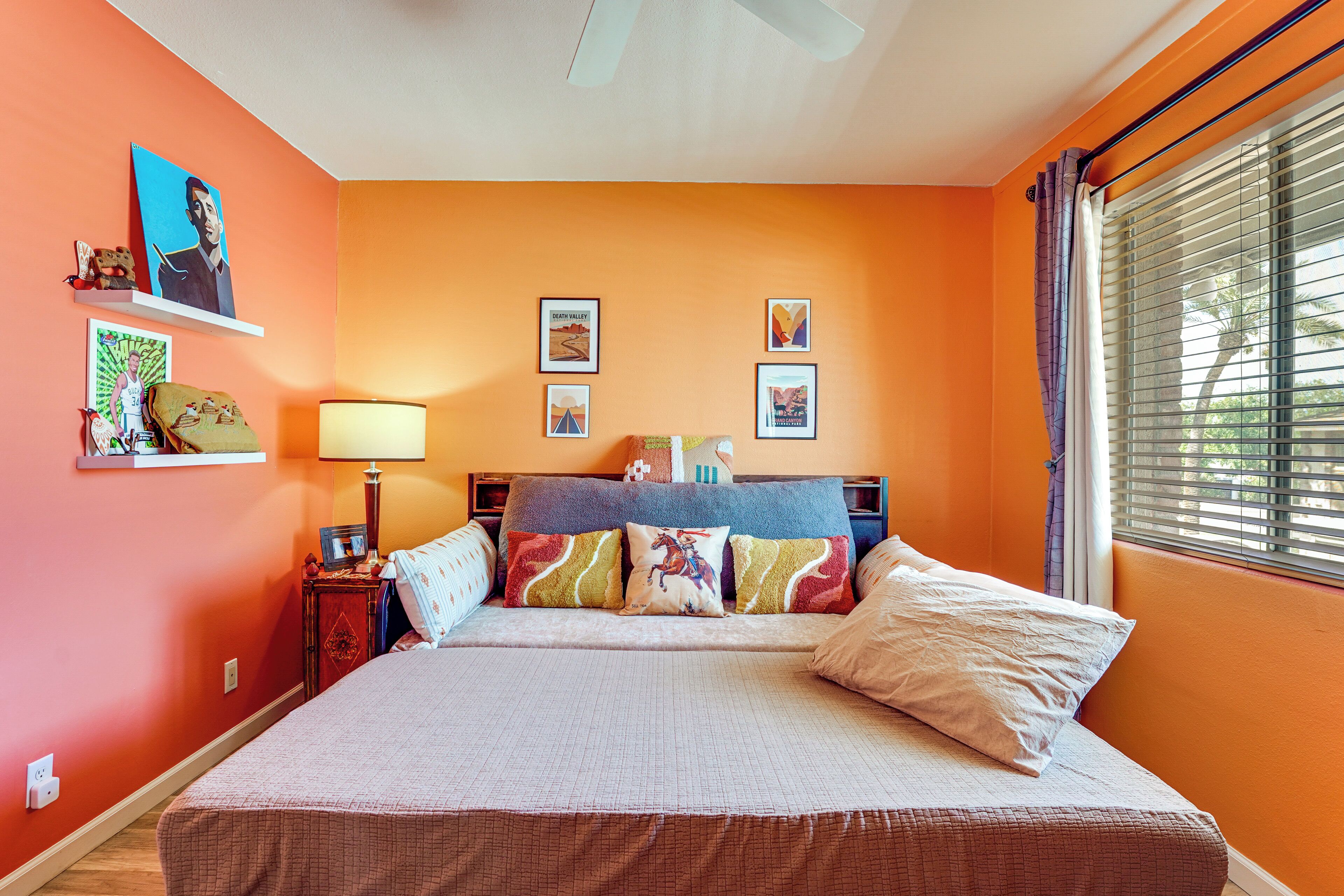 A bedroom with a bed, a nightstand, a lamp, and wall art.