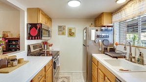 A kitchen with wooden cabinets, stainless steel appliances, a microwave, oven, and a refrigerator. - Steps to Fashion Square! Condo w/ Patio & Pool (Scottsdale)