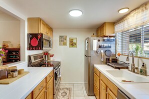 A kitchen with wooden cabinets, stainless steel appliances, a microwave, oven, and a refrigerator. - Steps to Fashion Square! Condo w/ Patio & Pool (Scottsdale)