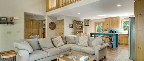 A spacious living area with a large L-shaped sectional sofa, a wooden coffee table, and a kitchen in the background.