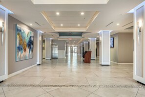 A hotel corridor with a modern design, featuring a long hallway, a large abstract painting on the left wall, and a podium on the right. - Relax Poolside, Walk to Shore! Daytona Beach Haven (Daytona Beach Shores)