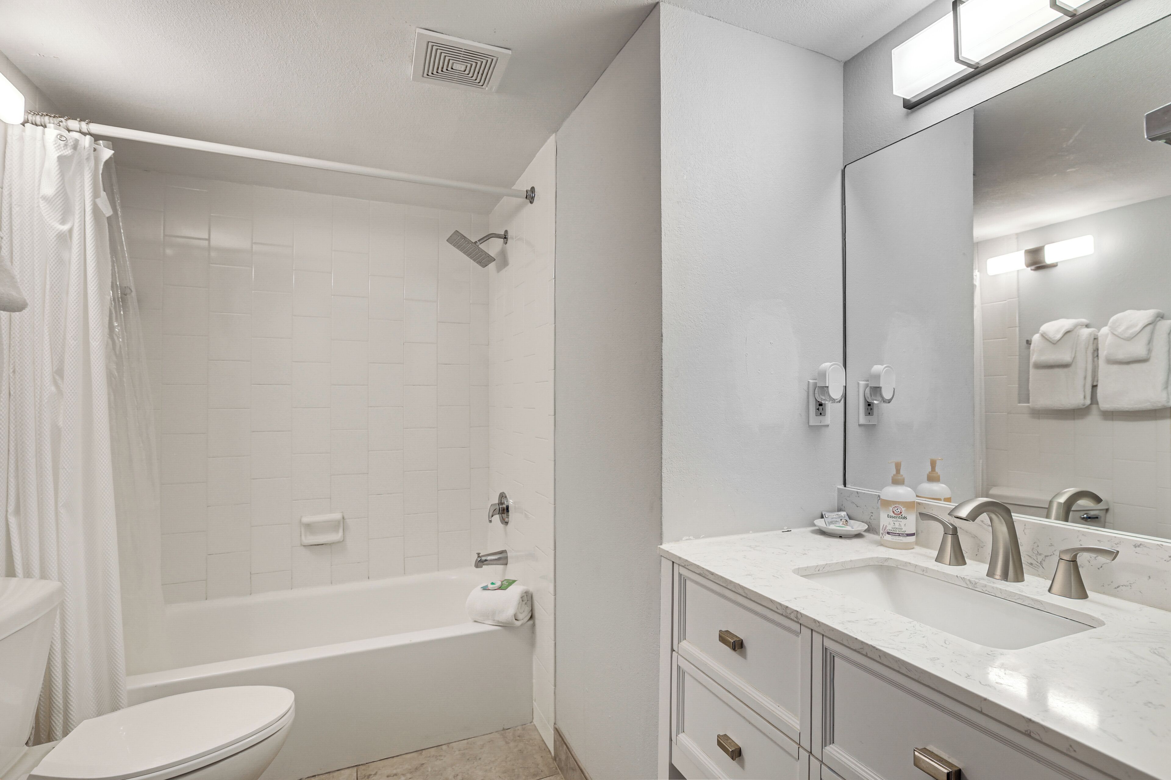 A modern bathroom with a bathtub, toilet, and vanity with a sink.